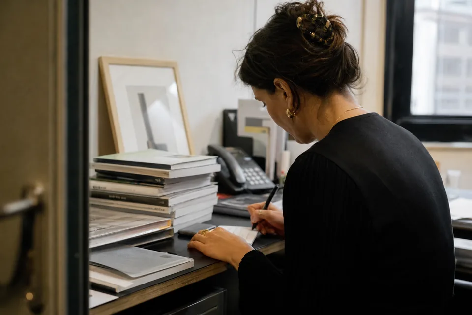 A gallery sales associate writes a collector's interests on an index card in the back office