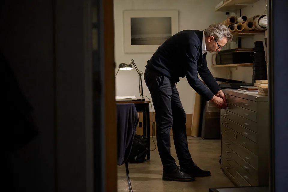 A gallery director locks the flat file storage cabinet in a quiet back room after closing