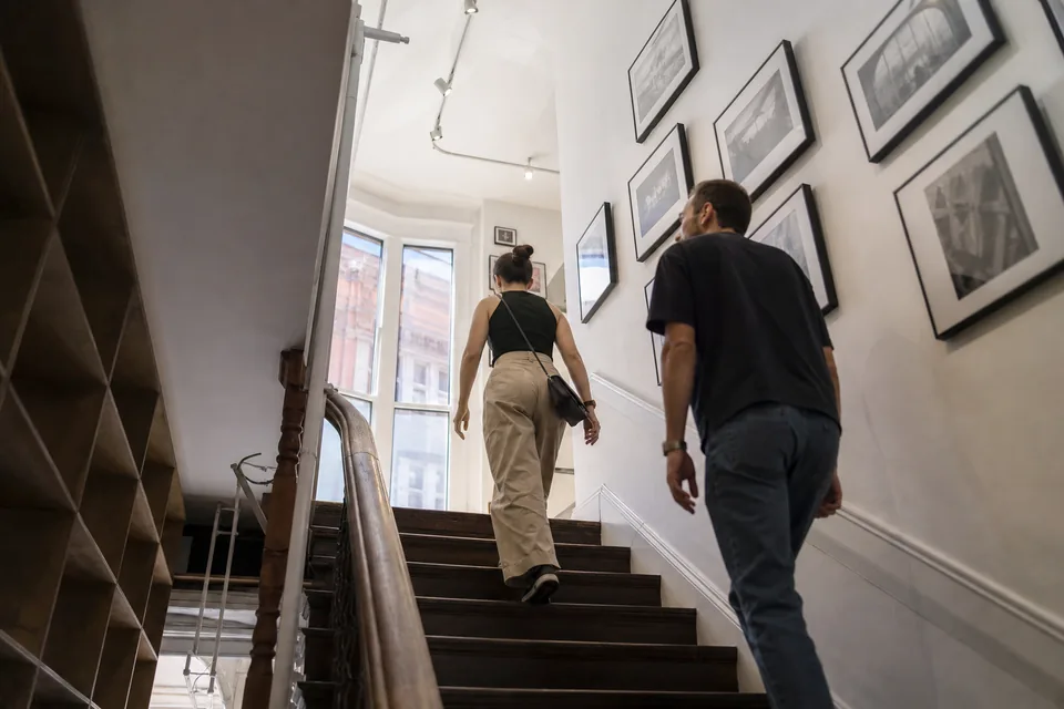 Visitors climb the stairs to a second floor gallery in an older building in San Francisco
